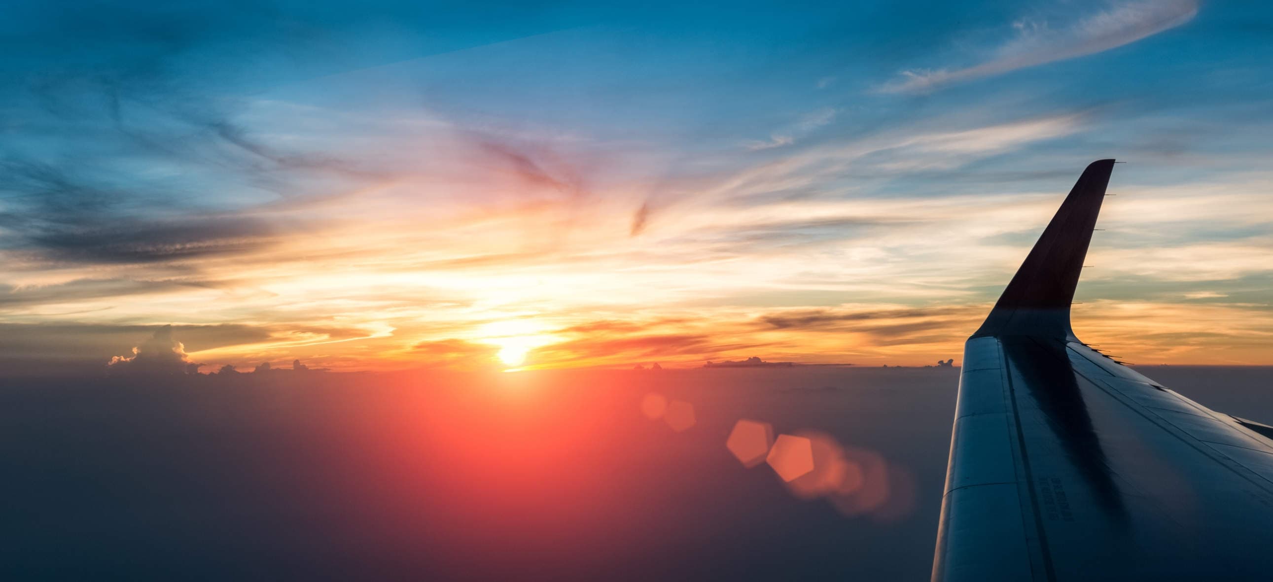 Private jet cruising above the clouds at sunset